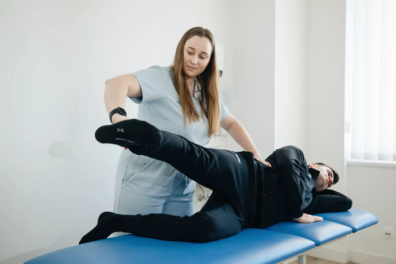 A physiotherapist stretching a patient’s leg on a treatment table.